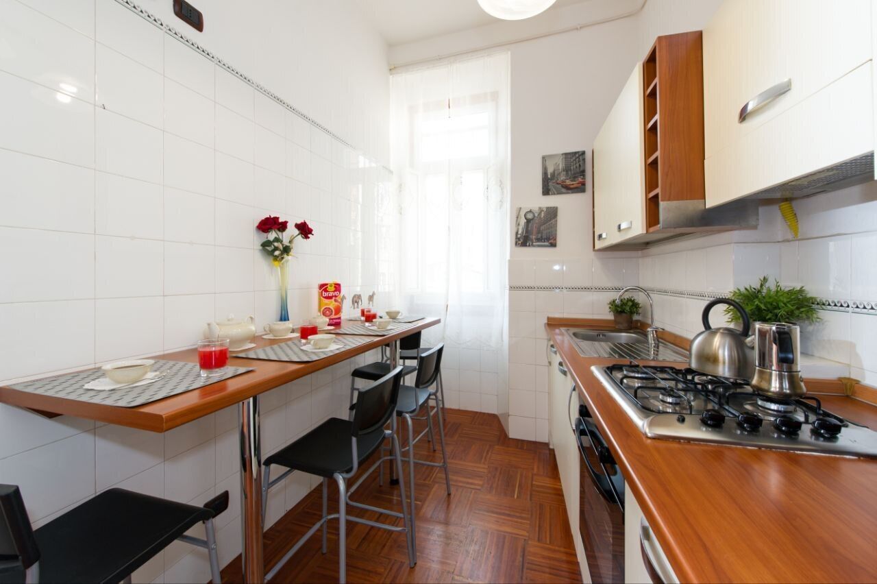 A compact kitchen with a wooden countertop, a gas stove, and white tiled walls.