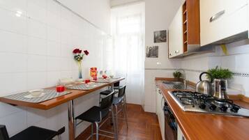 A compact kitchen with a wooden countertop, a gas stove, and white tiled walls.