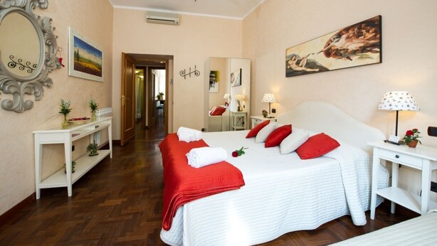 Una habitación de hotel con una cama grande, una mesita de noche, un espejo y un cuadro en la pared.