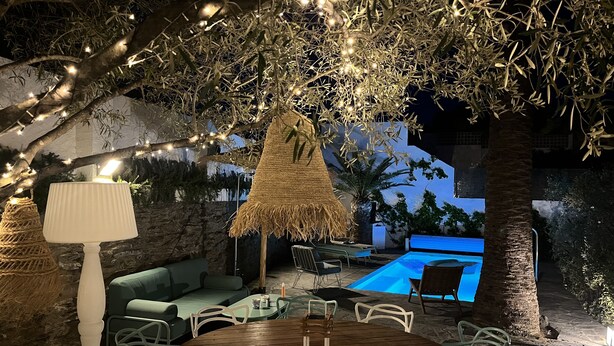 An outdoor seating area with a round wooden table, chairs, and a lamp.