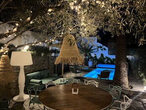 An outdoor seating area with a round wooden table, chairs, and a lamp. - A villa that feels like an oasis, with a Mediterranean garden and a heated pool in Cadaqués (Cadaqués)