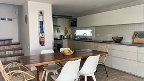 A modern kitchen with white cabinets, a wooden dining table, and white chairs.