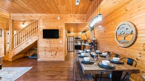 A wooden interior with a dining area, kitchen, and staircase.