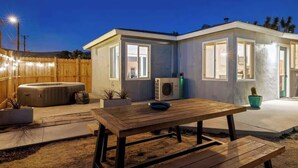Ett modernt hus med en uteplats, ett bubbelbad och ett bord.