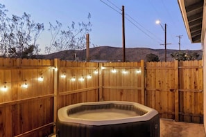 A hot tub in a wooden-fenced outdoor area with string lights. - Audrey's Place, New Hot Tub, Mins to Joshua Tree (Joshua Tree)