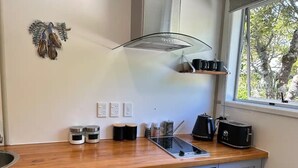 Une cuisine dotée d’un plan de travail en bois, d’un four encastré, d’un four à micro-ondes, d’un grille-pain et d’une fenêtre donnant sur les arbres.