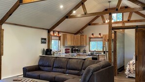 A spacious living area with a large sectional sofa, a coffee table, and a kitchen in the background.