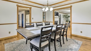 A dining room with a large table, six chairs, and a patterned rug.