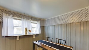 Un comedor con una mesa de madera, sillas y una ventana con cortinas blancas.