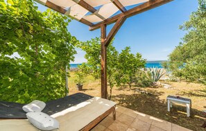 A sunlit outdoor seating area with a view of the sea, a wooden pergola, and a small table with a cushion. - Nice apartment in Dobropoljana with WiFi (Dobropoljana)