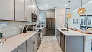 A modern kitchen with white cabinets, stainless steel appliances, and a marble floor.