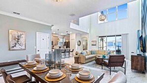 A spacious living area with a dining table set for six, a sofa, and a television.