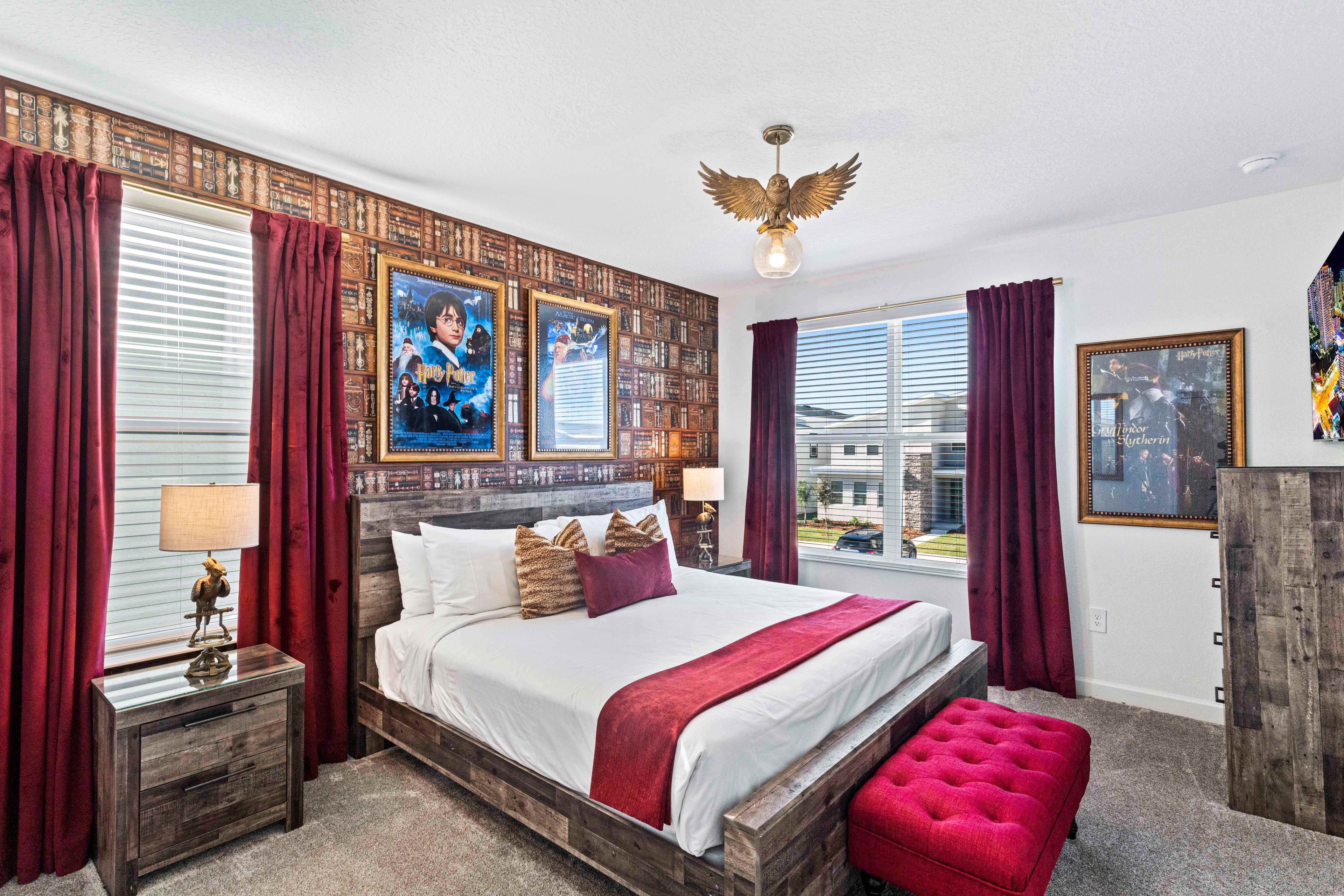 Un dormitorio con una cama grande, cortinas rojas, cabecero de madera y carteles en la pared.