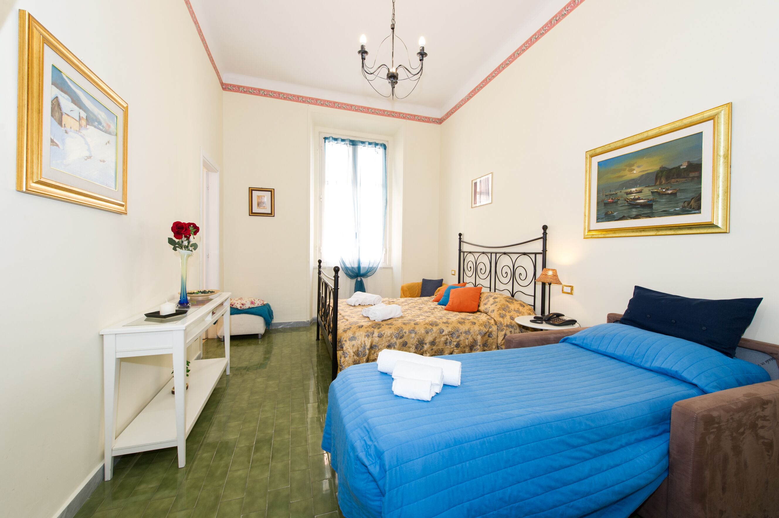 Un dormitorio con dos camas, una mesita de noche, una silla, una ventana con cortinas y un cuadro en la pared.