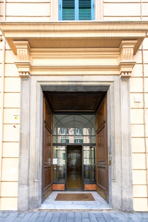A building entrance with a large wooden door, a glass window, and a number '33' on the wall. - Boezio House (Rome)