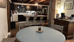 A cozy kitchen with a central island, bar stools, and a dining table with chairs.