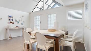 A spacious dining area with a high ceiling and skylight, white walls, and a modern design.