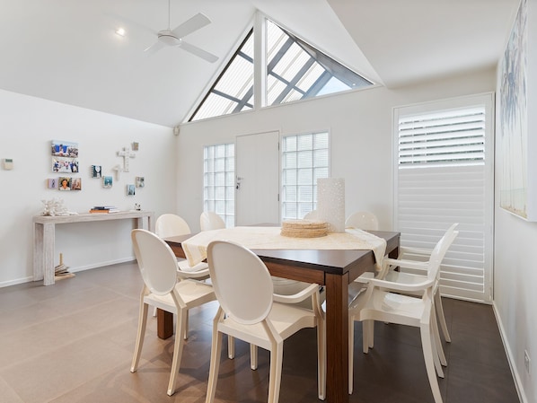 A spacious dining area with a high ceiling and skylight, white walls, and a modern design.