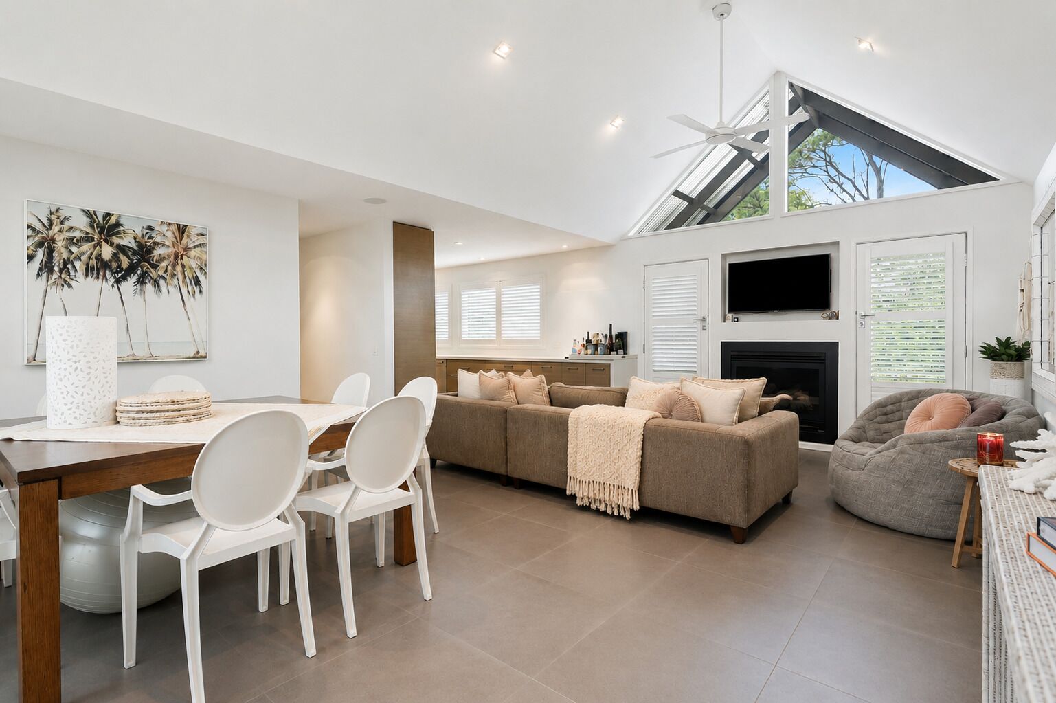 A modern living room with a sofa, chairs, a dining table, and a fireplace.