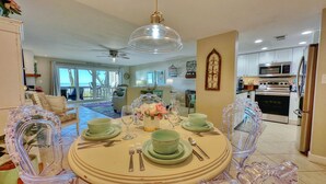 A dining area with a round table set for four, surrounded by clear glass chairs. - Beachfront Paradise, Retro Twist, Exquisite Views, Private Entrance, EV Car Charger!   (Indian Shores)