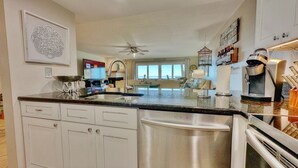 A modern kitchen with a central island, stainless steel appliances, and a view to the living area. - Beachfront Paradise, Retro Twist, Exquisite Views, Private Entrance, EV Car Charger!   (Indian Shores)