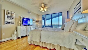 Een slaapkamer met een groot bed, een televisie en uitzicht op de oceaan.