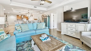 A spacious living room with a blue sofa, a coffee table, and a television. - Stunning & Spacious Waterfront, French Country Coastal Style, Complex Pool & Hot Tub!   (Clearwater)