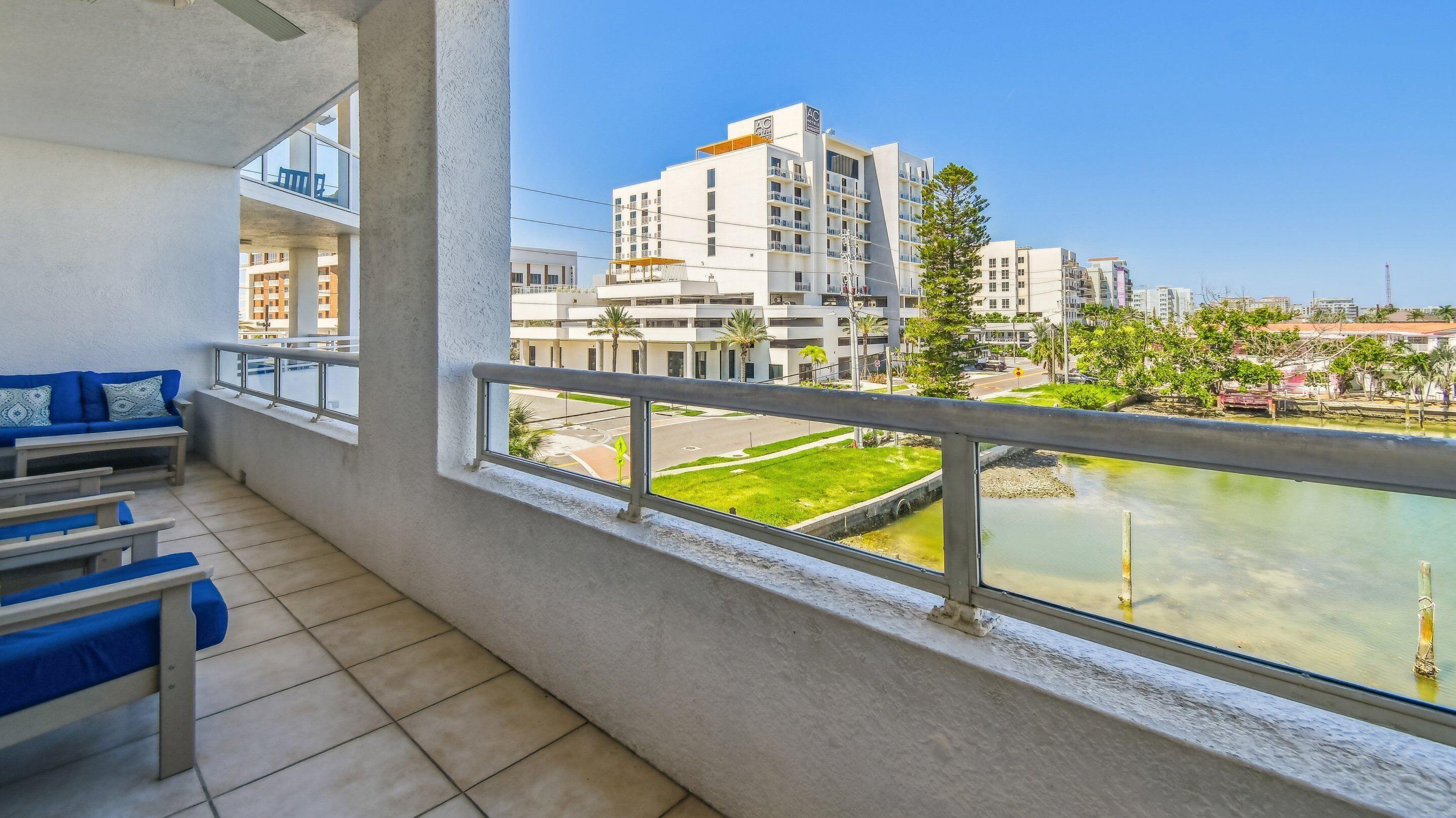 Ein Balkon mit Blick auf ein modernes Gebäude, eine Rasenfläche und ein Gewässer.
