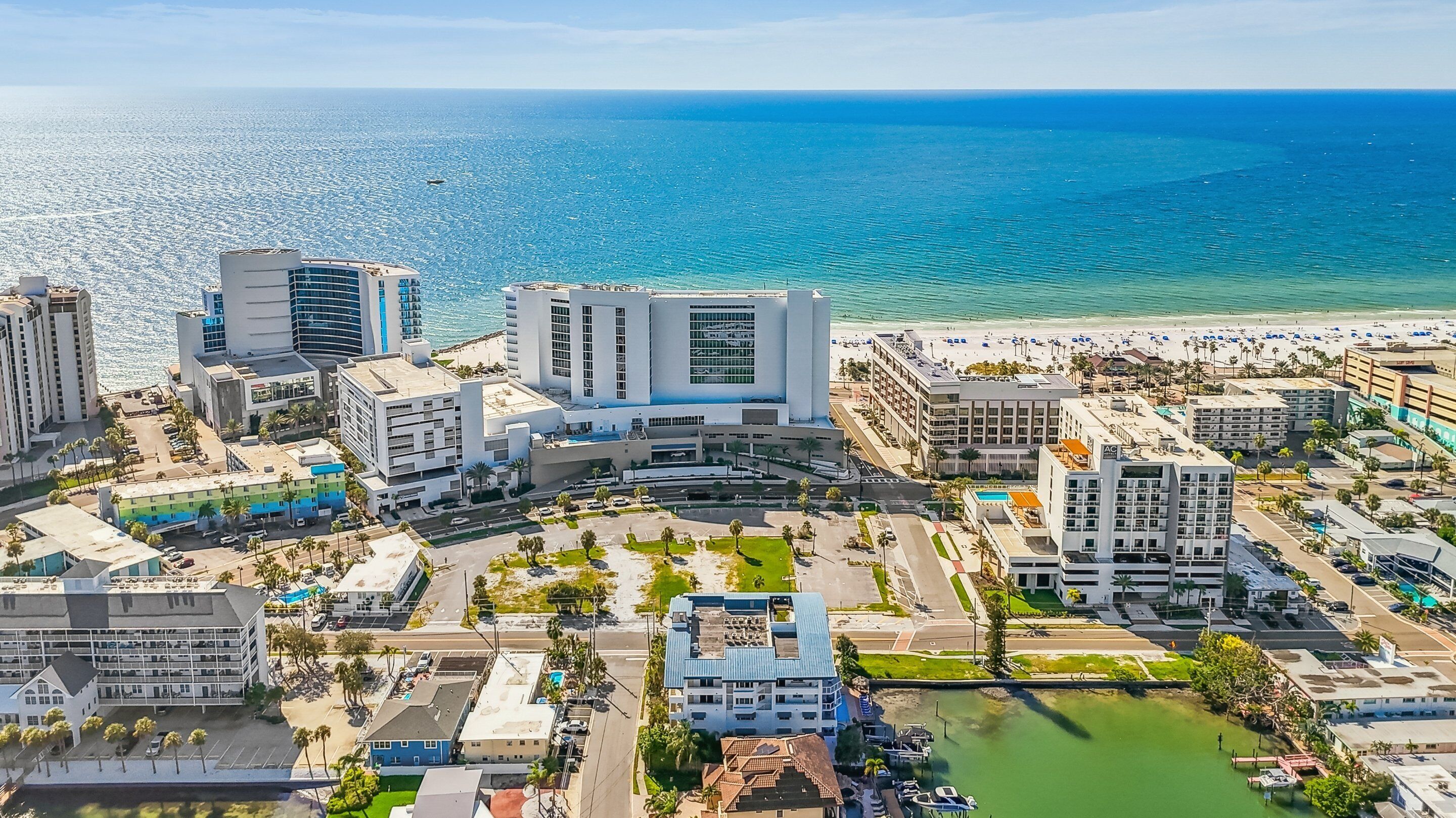 An aerial view of a coastal city with modern buildings, a marina, and a beach.
