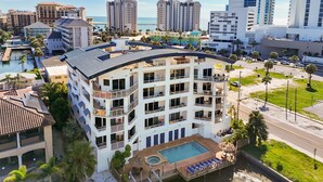 A multi-story hotel with balconies, a swimming pool, and a view of the ocean. - Stunning & Spacious Waterfront, French Country Coastal Style, Complex Pool & Hot Tub!   (Clearwater)