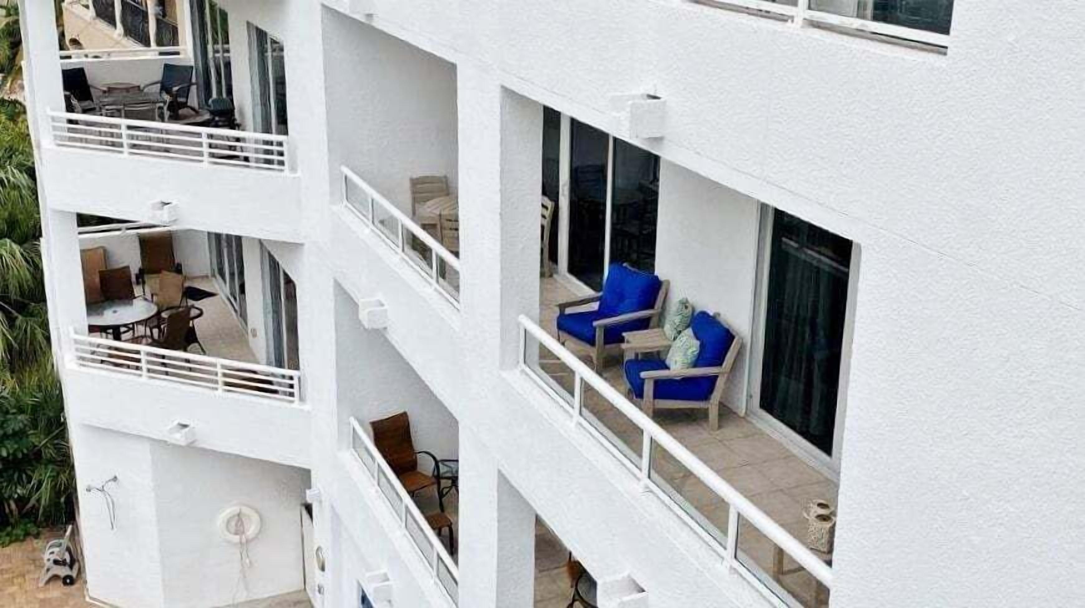 A multi-story building with balconies, outdoor seating, and large windows.