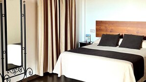 Ein Hotelzimmer mit einem großen Bett, einem Holzkopfende, einem Spiegel und einem Vorhang.