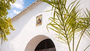A white building with a large arched doorway and a small religious icon above it.