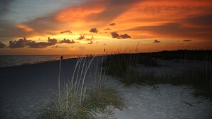 A beach with sand dunes and a sunset.