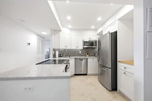 A modern kitchen with white cabinetry, stainless steel appliances, and a tiled backsplash.