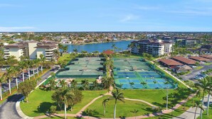 A coastal residential area with multiple buildings, a marina, and tennis courts.