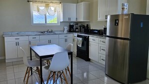 Een moderne keuken met witte kastjes, een roestvrijstalen koelkast en een eettafel met stoelen.
