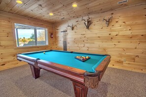 A pool table with a set of balls, a window with a view, and wall-mounted antlers. - Lone Star Lodge - Gorgeous Lodge in Hocking Hills (Logan)