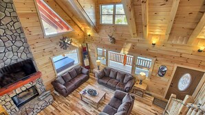 A spacious living area with a stone fireplace, wooden flooring, and brown leather sofas. - Lone Star Lodge - Gorgeous Lodge in Hocking Hills (Logan)