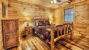 A wooden cabin bedroom with a bed, nightstands, and a ceiling fan. - Lone Star Lodge - Gorgeous Lodge in Hocking Hills (Logan)