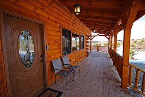 A wooden cabin with a covered porch, two chairs, and a door with a stained glass window. - Lone Star Lodge - Gorgeous Lodge in Hocking Hills (Logan)