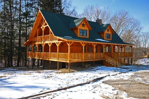A log cabin with a balcony and a chimney, surrounded by snow and trees. - Lone Star Lodge - Gorgeous Lodge in Hocking Hills (Logan)