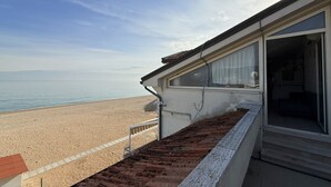 A beachfront property with a balcony overlooking the sea, a covered outdoor area, and a building with large windows. - M170 - Marcelli, Wonderful attic with sea view (Marcelli)