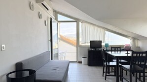 A modern room with a sofa, a dining table with chairs, a television, and a view through a large window. - M170 - Marcelli, Wonderful attic with sea view (Marcelli)