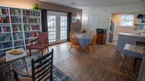 Una sala de estar acogedora con una estantería, un comedor con mantel a cuadros y una cocina con microondas.