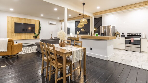 Une cuisine moderne avec une table à manger en bois, des chaises et un îlot central intégré.