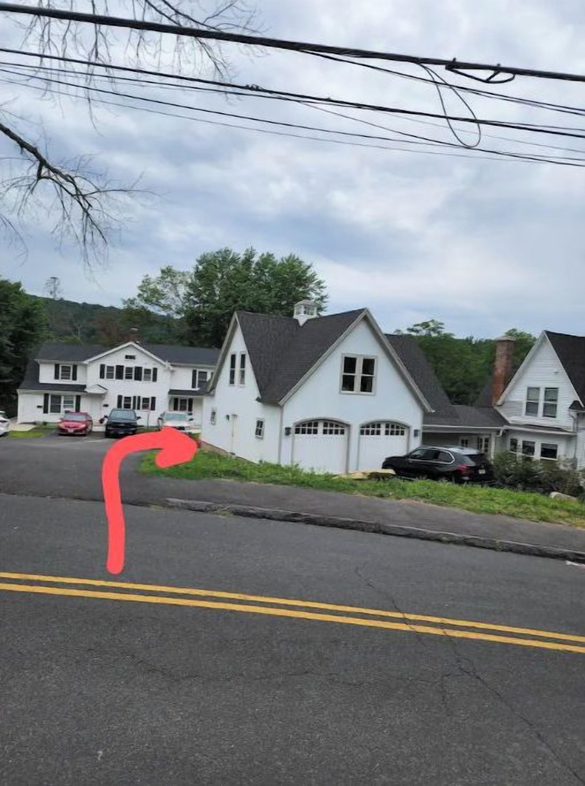 A residential street with houses, a curved road, and parked cars.