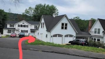 A residential street with houses, a curved road, and parked cars.