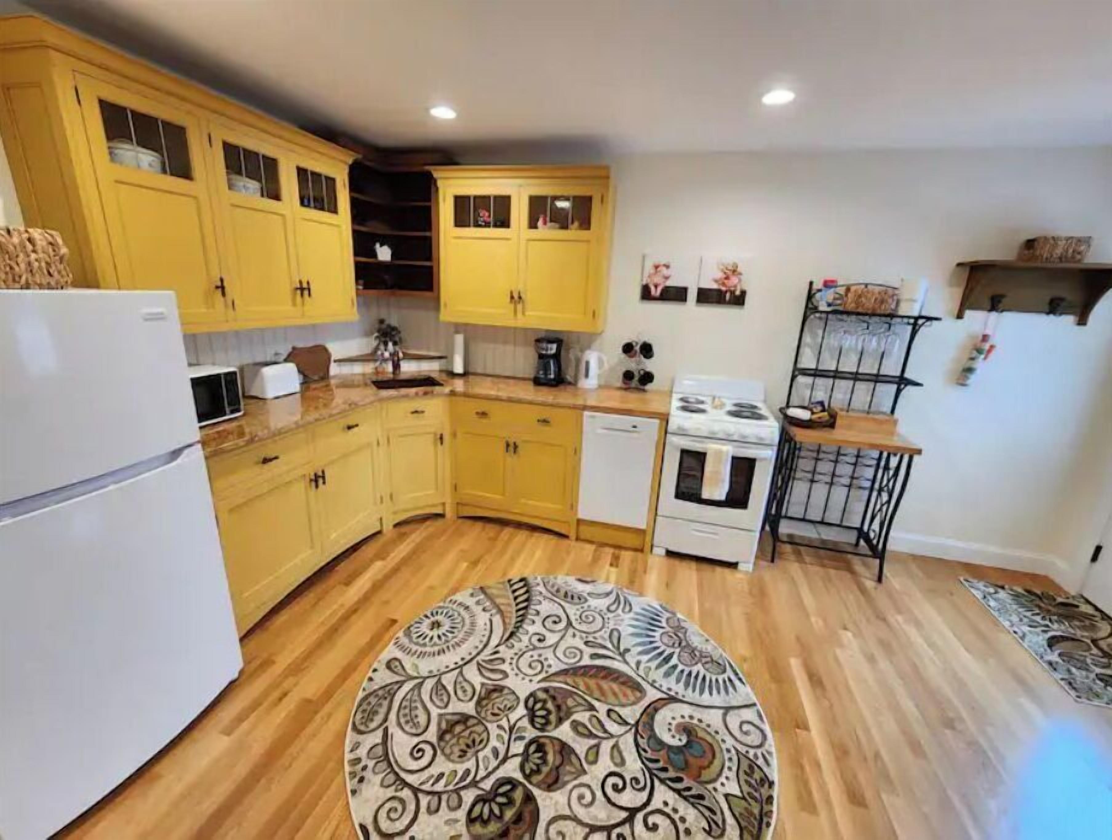 A compact kitchen with yellow cabinets, a white refrigerator, a stove, and a microwave.