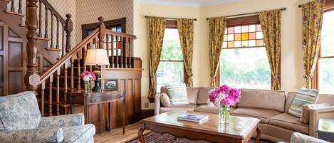 A spacious living room with a wooden staircase, a sofa set, and a coffee table.